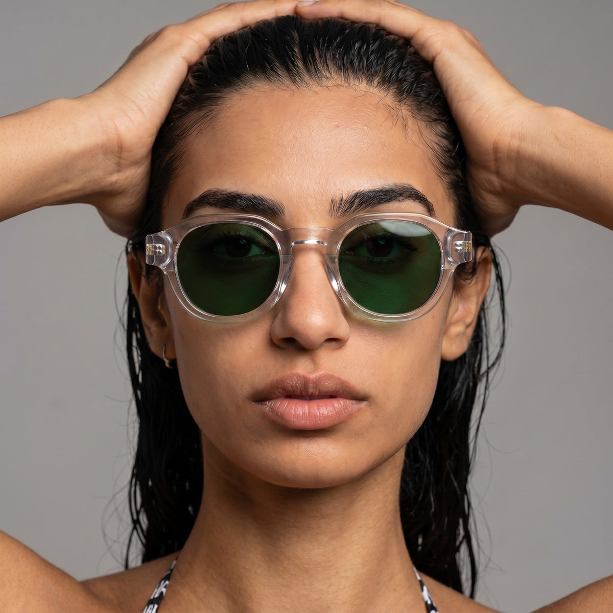 Woman wearing nadaraty eyewear Horus Pro H 178 sunglasses with clear frames and dark green lenses